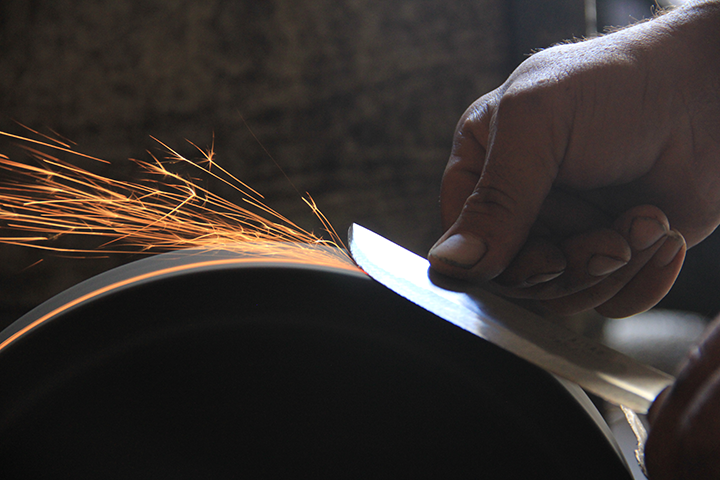 man-sharpening-knife-on-grind-stone-with-sparks-flying