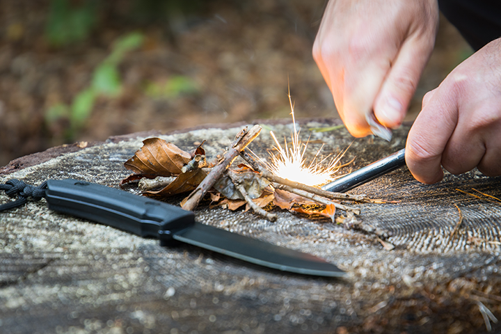 mans-hands-striking-fire-steel-on-log-igniting-fire