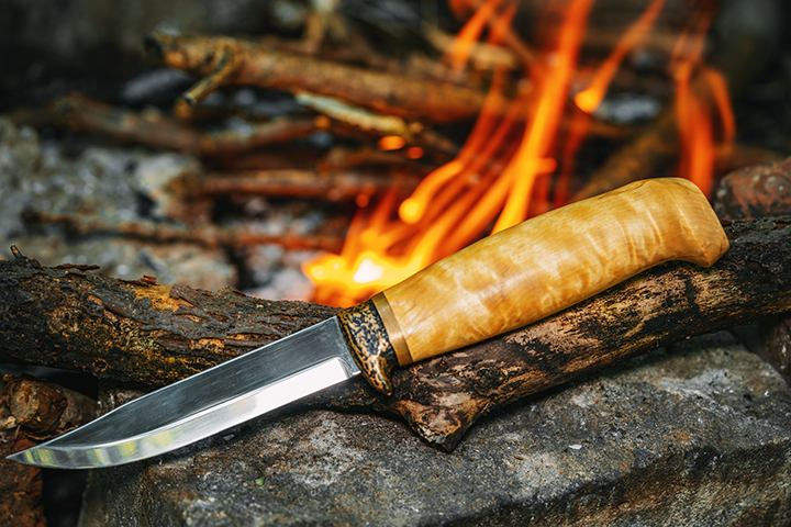 wooden-handle-bushcraft-knife-sitting-on-rock-in-front-of-fire